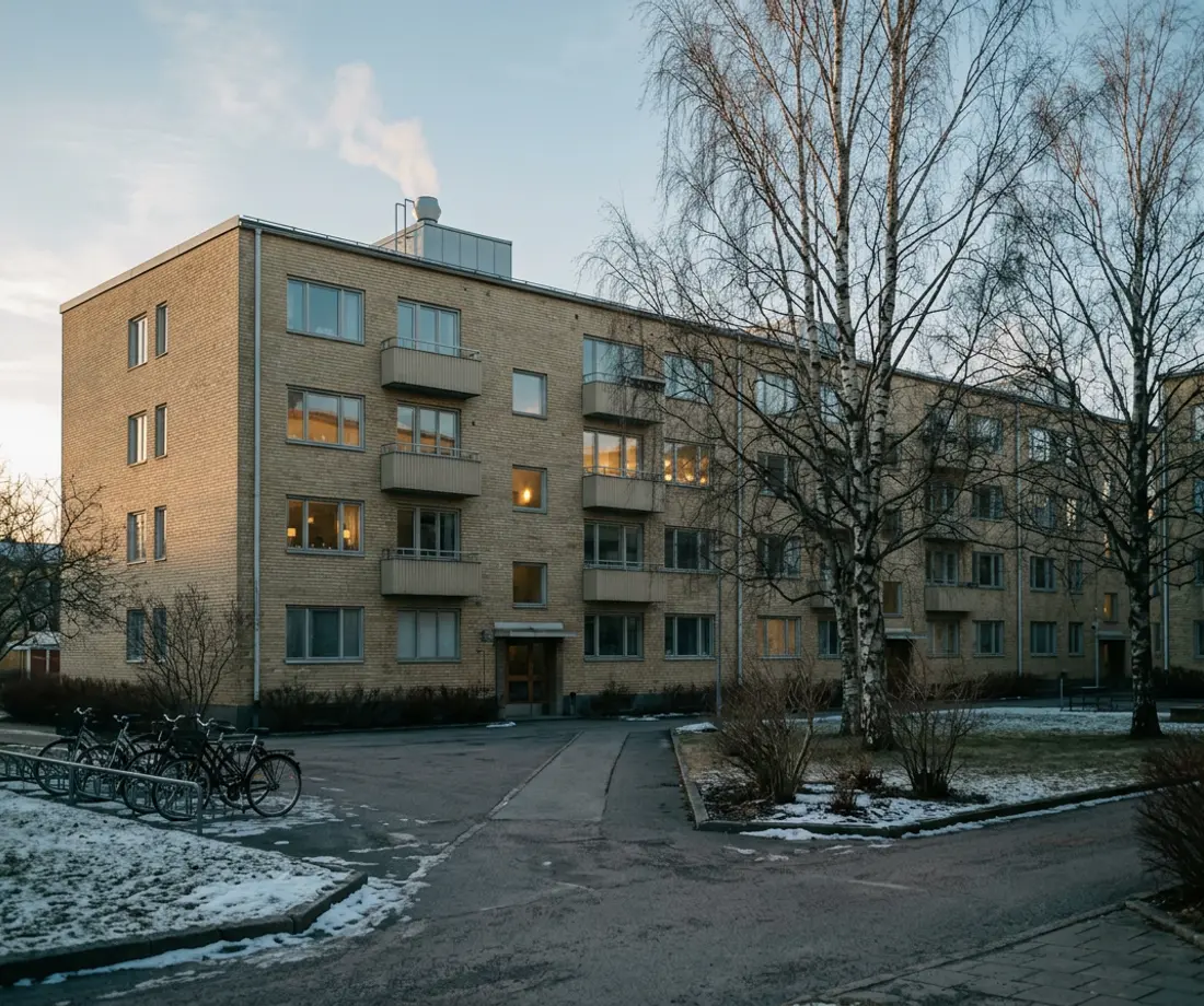 Flerbostadshus i gult tegel från 1960-talet en vinterdag, med ljus i några fönster